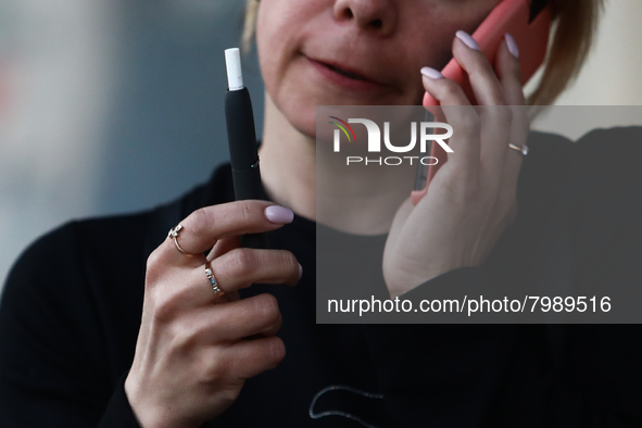 A woman smokes a cigarette using a tobacco heater
 in Krakow, Poland on March 28, 2022. 