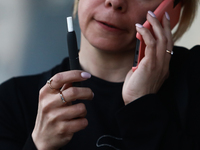 A woman smokes a cigarette using a tobacco heater
 in Krakow, Poland on March 28, 2022. (