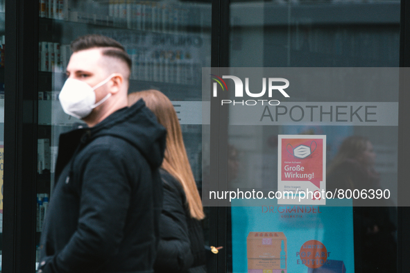 a couple walks pass a apotheke with  mask sign is seen in city center of Bonn, Germany on April 2, 2022 as many rules of covid 19 will be ex...