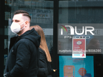 a couple walks pass a apotheke with  mask sign is seen in city center of Bonn, Germany on April 2, 2022 as many rules of covid 19 will be ex...