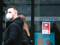 a couple walks pass a apotheke with  mask sign is seen in city center of Bonn, Germany on April 2, 2022 as many rules of covid 19 will be ex...