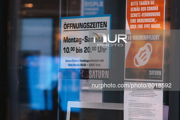 "please wear face mask in our store" sign is seen in front of Saturn, the electronic store in the city center of Cologne, Germany on April 4...