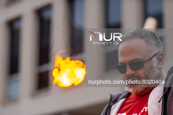 A 50-year-old man with debt as a result of going to college later in life, sets fire to a small piece of paper symbolizing his student debt...