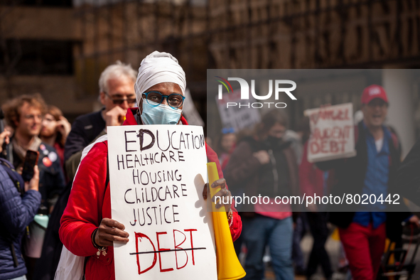 A protester carries a sign listing the things necessary for life, with the exception of debt, at a rally to cancel student debt at the Depar...