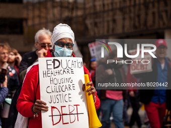 A protester carries a sign listing the things necessary for life, with the exception of debt, at a rally to cancel student debt at the Depar...