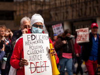 A protester carries a sign listing the things necessary for life, with the exception of debt, at a rally to cancel student debt at the Depar...