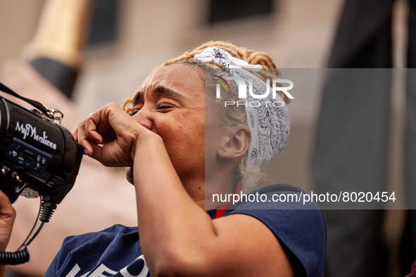 A protester chokes up while speaking about the harmful effects student debt has had on her life during a rally to cancel educational debt at...