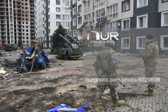 Ukrainian servicemen stands near Destroyed civil vehicles  near a damaged residential building in the recaptured by the Ukrainian army Bucha...