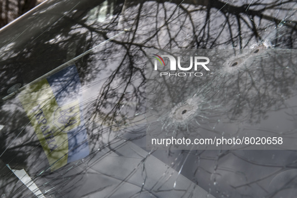 Ukrainian flag and Bullet holes on a screen of shelled civil car in the recaptured by the Ukrainian army Bucha city near Kyiv, Ukraine, 04 A...