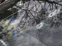 Ukrainian flag and Bullet holes on a screen of shelled civil car in the recaptured by the Ukrainian army Bucha city near Kyiv, Ukraine, 04 A...