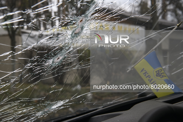 Ukrainian flag and Bullet holes on a screen of shelled civil car in the recaptured by the Ukrainian army Bucha city near Kyiv, Ukraine, 04 A...