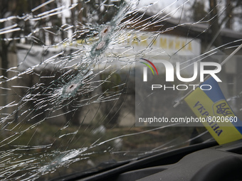 Ukrainian flag and Bullet holes on a screen of shelled civil car in the recaptured by the Ukrainian army Bucha city near Kyiv, Ukraine, 04 A...