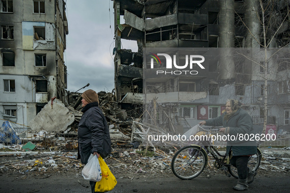 A couple of women  of Borodianka with bags of humanitarian aid, passes near a destroyed building after the combats between the russian and u...