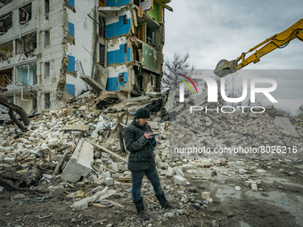 A woman checks in her phone the list of belongings recovered in the debris of her flat destroyed in the combats between the ukrainian and ru...
