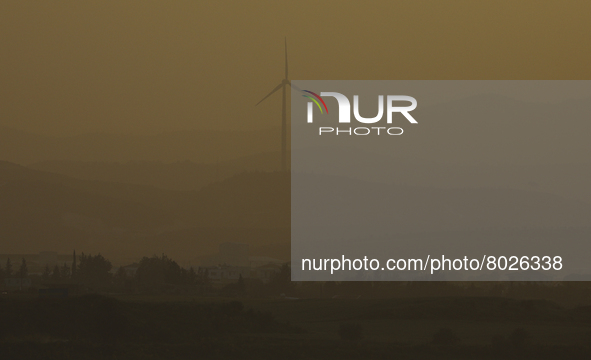 Haze hangs over a wind turbine at sunset in Larnaca. Cyprus, Wednesday, April 6, 2022. The U.N. health agency says nearly everybody in the w...