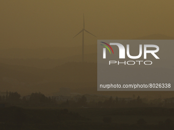 Haze hangs over a wind turbine at sunset in Larnaca. Cyprus, Wednesday, April 6, 2022. The U.N. health agency says nearly everybody in the w...