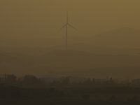 Haze hangs over a wind turbine at sunset in Larnaca. Cyprus, Wednesday, April 6, 2022. The U.N. health agency says nearly everybody in the w...