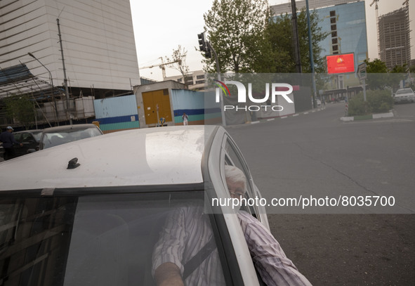 An Iranian internet taxi driver wearing a protective face mask as he sits in his vehicle on a corner of a square in Tehran during a polluted...