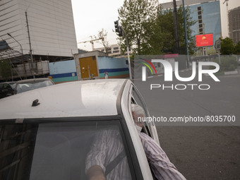 An Iranian internet taxi driver wearing a protective face mask as he sits in his vehicle on a corner of a square in Tehran during a polluted...