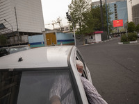 An Iranian internet taxi driver wearing a protective face mask as he sits in his vehicle on a corner of a square in Tehran during a polluted...