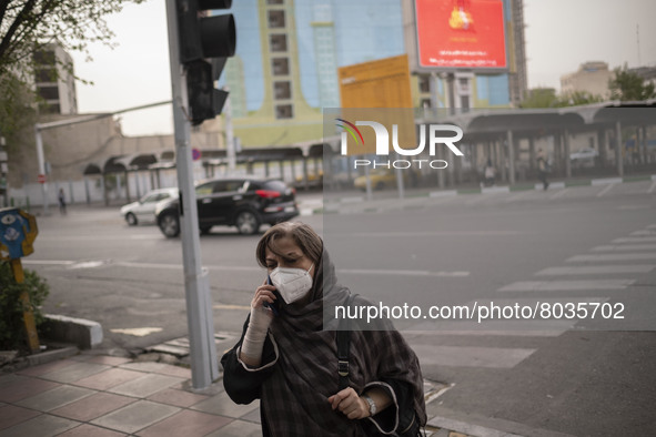 An Iranian woman wearing a protective face mask speaks on her smartphone as she walks along a street-side in Tehran during a polluted air, o...