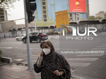 An Iranian woman wearing a protective face mask speaks on her smartphone as she walks along a street-side in Tehran during a polluted air, o...