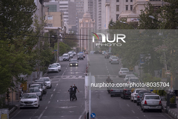 An Iranian couple wearing protective face masks cross a street in Tehran during a polluted air, on April 8, 2022. 