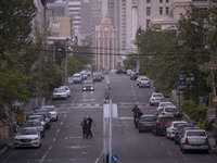 An Iranian couple wearing protective face masks cross a street in Tehran during a polluted air, on April 8, 2022. (