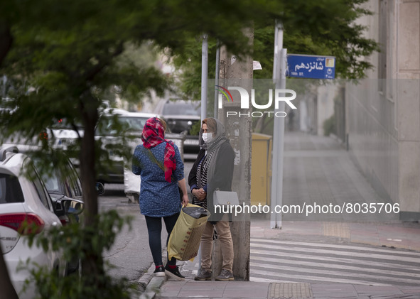 Two Iranian women speak with each other while standing on a street-side in Tehran during a polluted air, on April 8, 2022. 