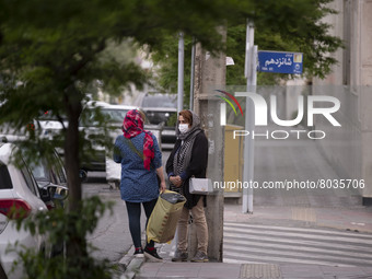 Two Iranian women speak with each other while standing on a street-side in Tehran during a polluted air, on April 8, 2022. (