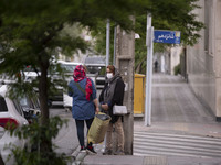 Two Iranian women speak with each other while standing on a street-side in Tehran during a polluted air, on April 8, 2022. (