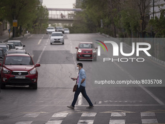 An Iranian man wearing a protective face mask crosses an avenue in Tehran during a polluted air, on April 8, 2022. (