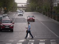 An Iranian man wearing a protective face mask crosses an avenue in Tehran during a polluted air, on April 8, 2022. (