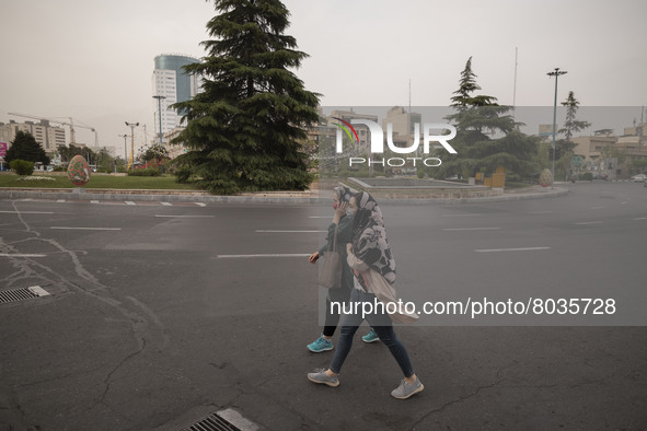 Two Iranian women wearing protective face masks walk along an avenue in Tehran during a polluted air, on April 8, 2022. 