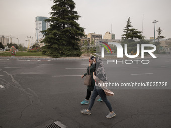 Two Iranian women wearing protective face masks walk along an avenue in Tehran during a polluted air, on April 8, 2022. (