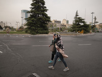 Two Iranian women wearing protective face masks walk along an avenue in Tehran during a polluted air, on April 8, 2022. (