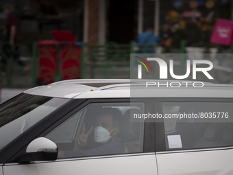 An Iranian driver wearing a protective face mask flashes a Victory sign as a reaction to the camera while driving his vehicle along an avenu...