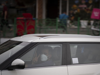 An Iranian driver wearing a protective face mask flashes a Victory sign as a reaction to the camera while driving his vehicle along an avenu...