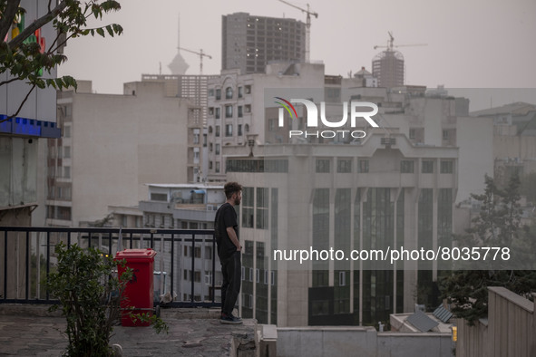 An Iranian man stands on a street-side as a view of downtown Tehran during a polluted air, on April 8, 2022. 