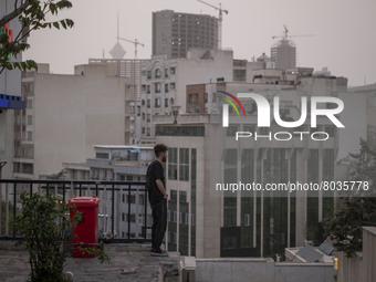 An Iranian man stands on a street-side as a view of downtown Tehran during a polluted air, on April 8, 2022. (