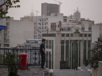 An Iranian man stands on a street-side as a view of downtown Tehran during a polluted air, on April 8, 2022. (