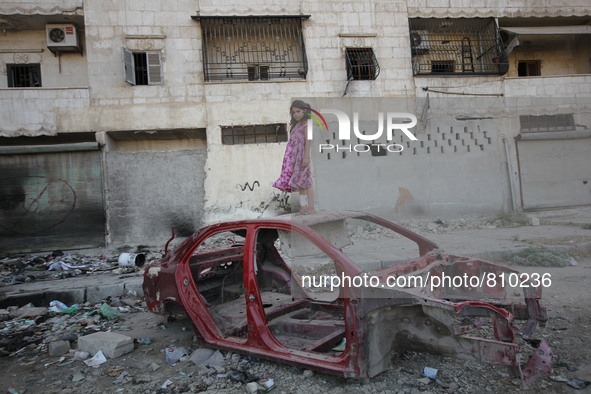 A little girl is standing on a damaged car at the al-Mashhd neighbourhood of the northern Syrian city of Aleppo on September 27, 2015  