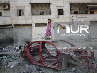 A little girl is standing on a damaged car at the al-Mashhd neighbourhood of the northern Syrian city of Aleppo on September 27, 2015  (