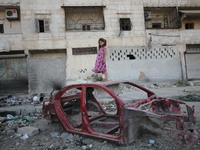 A little girl is standing on a damaged car at the al-Mashhd neighbourhood of the northern Syrian city of Aleppo on September 27, 2015  (
