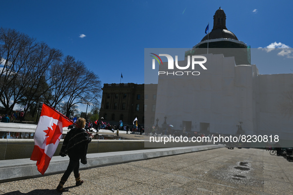 A woman carrying the Canadian flag walks in front Alberta Legislature.
Health-care workers, activists and their supporters protest against P...