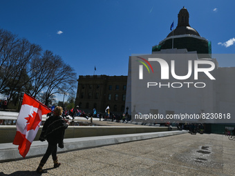 A woman carrying the Canadian flag walks in front Alberta Legislature.
Health-care workers, activists and their supporters protest against P...