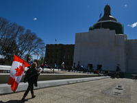 A woman carrying the Canadian flag walks in front Alberta Legislature.
Health-care workers, activists and their supporters protest against P...