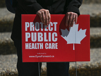 A protester holds a placard with words 'Protect Public Health Care'.
Health-care workers, activists and their supporters protested this afte...