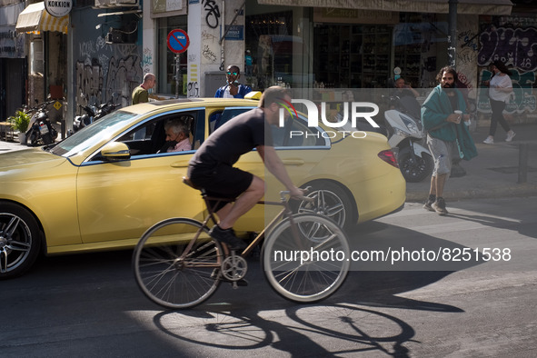 A man is passing in front of a Taxi riding bicycle near Monastiraki square in Athens, Greece on May 18, 2022. A committee of experts from th...