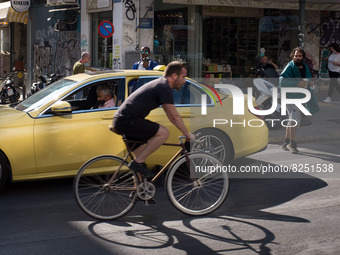 A man is passing in front of a Taxi riding bicycle near Monastiraki square in Athens, Greece on May 18, 2022. A committee of experts from th...